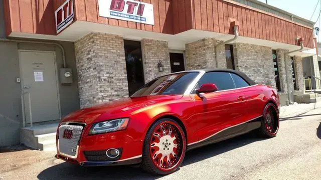 Red custom convertible Audi parked in front of DTI building with matching red rims.