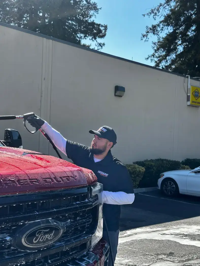 Highline Auto Care pressure washing a Ford Super Duty at a customer's home