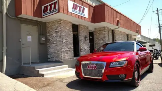 Red Audi parked in front of a brick building with