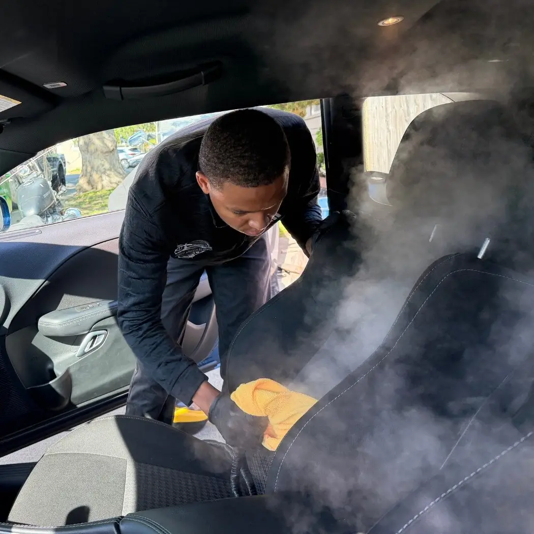 Jalil steam cleaning a rear seat during a mobile interior detail